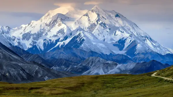 Majestatyczny, ośnieżony szczyt Denali, jednego z najwyższych szczytów kontynentów, góruje nad surowym krajobrazem.